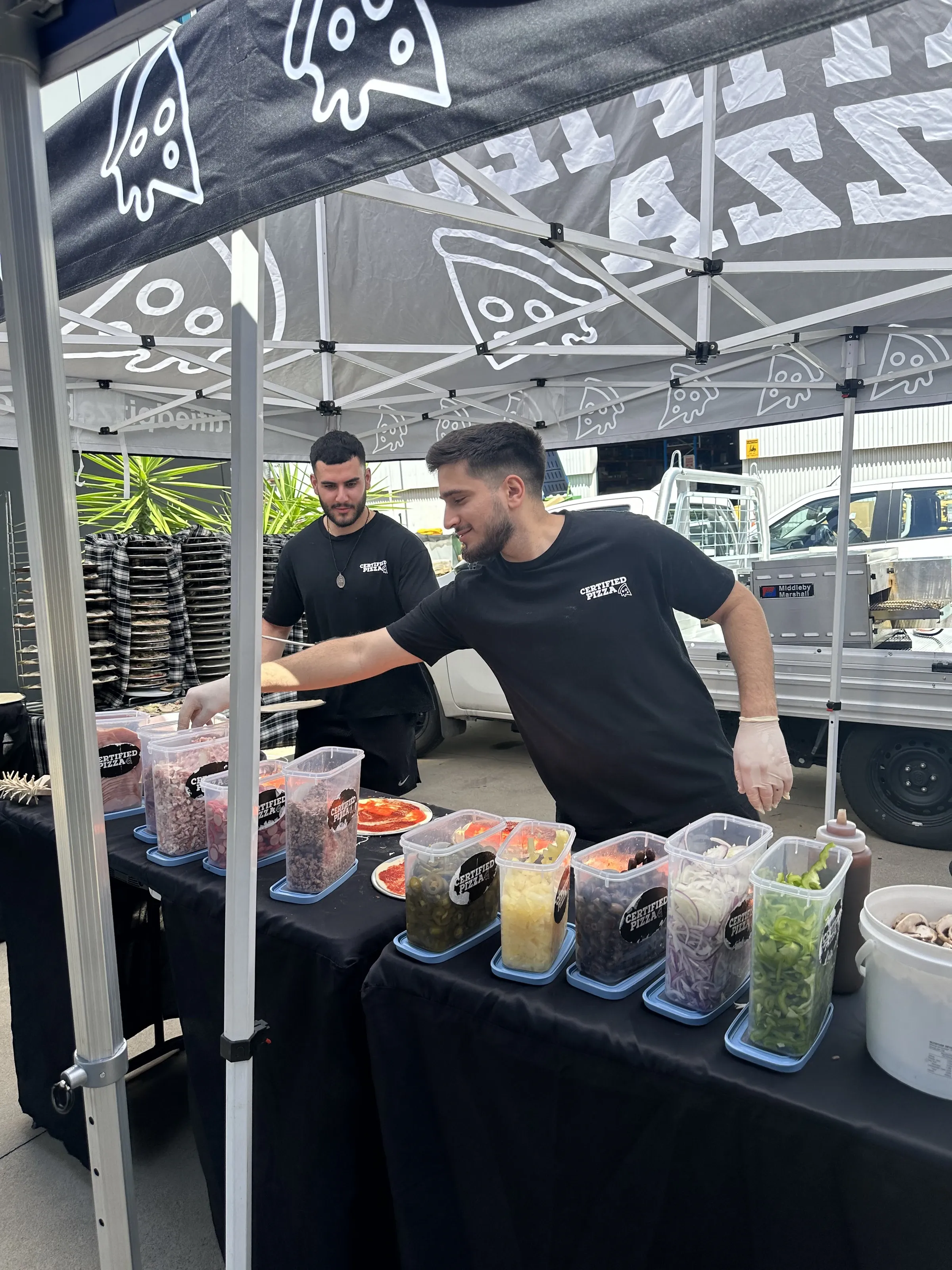 Certified Pizza team preparing toppings under the marquee at Komatsu Fairfield